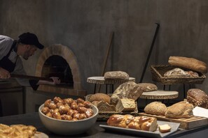 Una panadería con un horno, diferentes panes y pasteles expuestos sobre mesas.