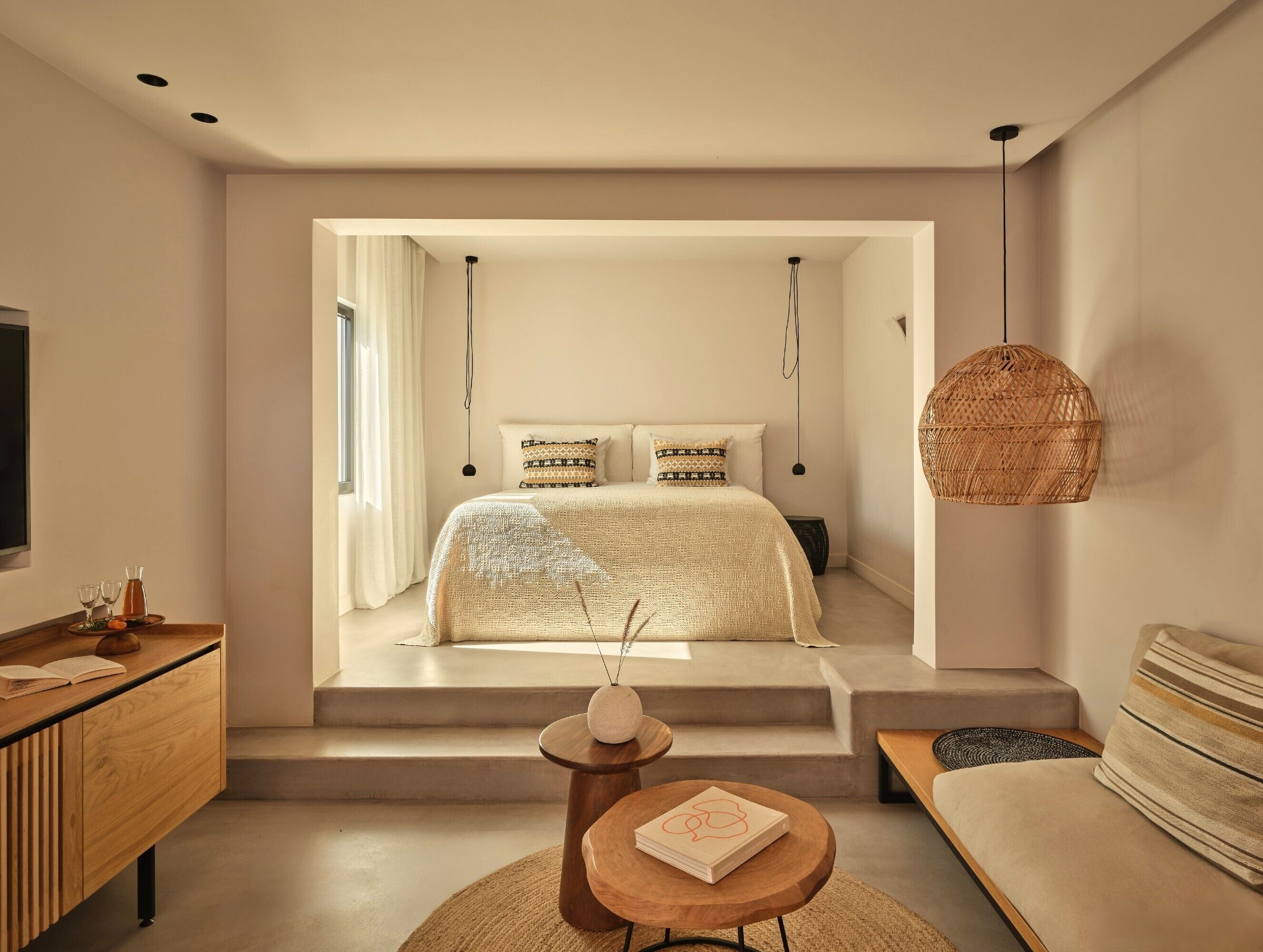 A modern bedroom with a large bed, a wooden desk, and a wicker hanging light fixture.