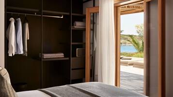 A bedroom with a bed, a wardrobe, and a view of a pool and beach.
