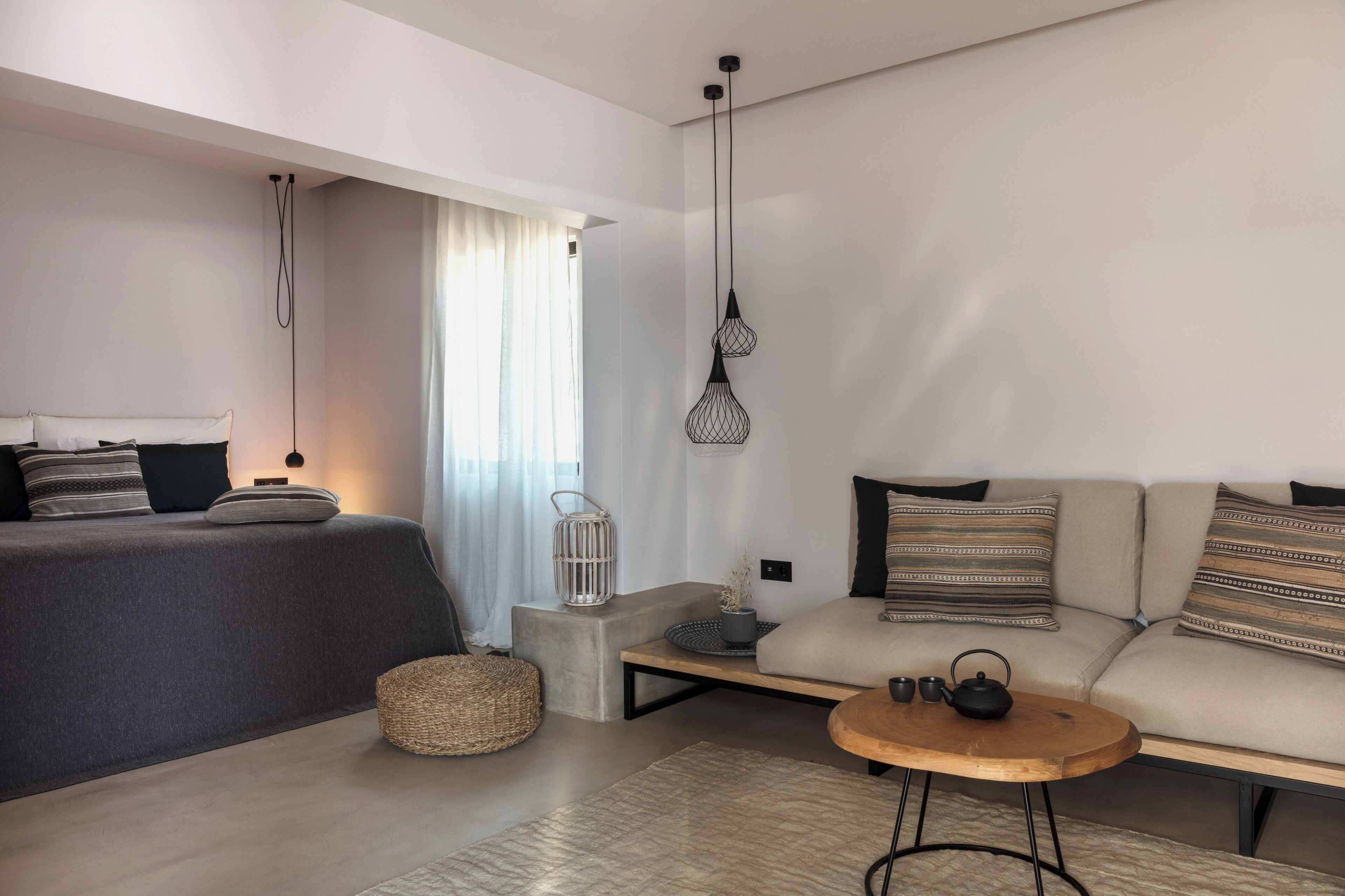 A modern, well-lit room with a bed, sofa, and a small table.