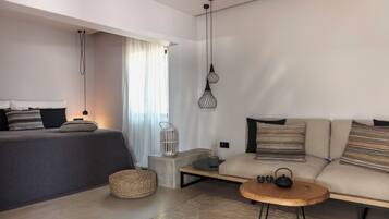 A modern, well-lit room with a bed, sofa, and a small table.