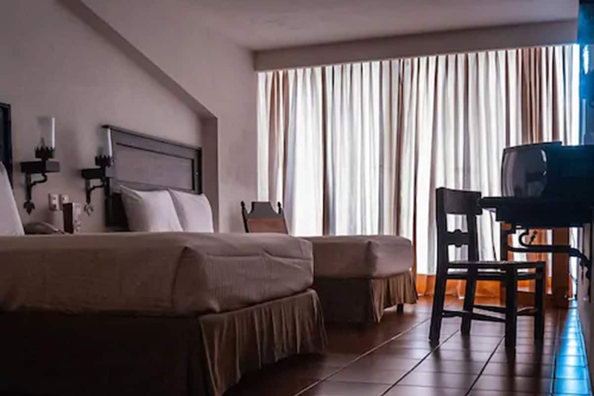 Una habitación de hotel con una cama, un escritorio y una silla.