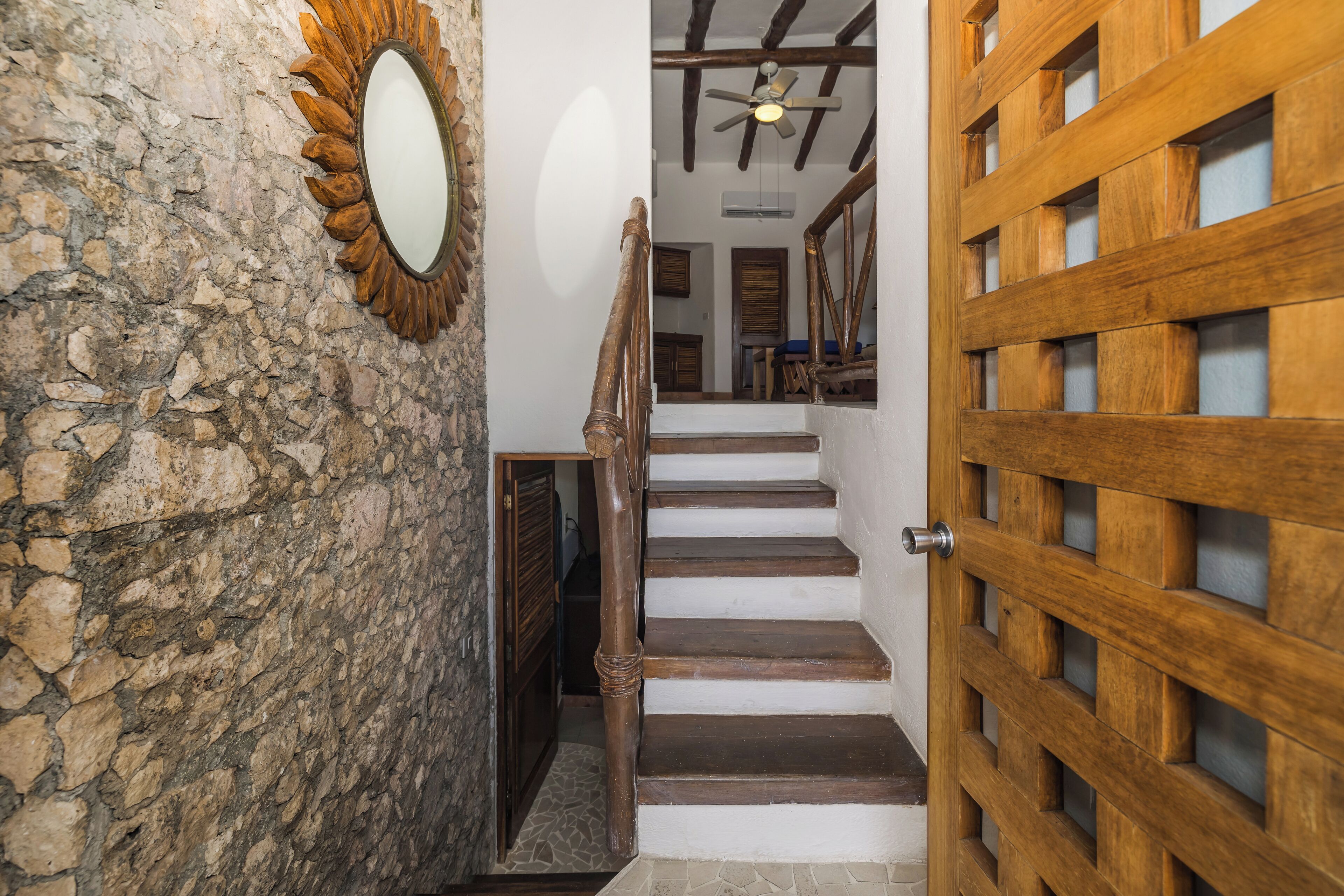 Un escalier avec des marches en bois et une porte en bois ornée d’un motif en treillis.