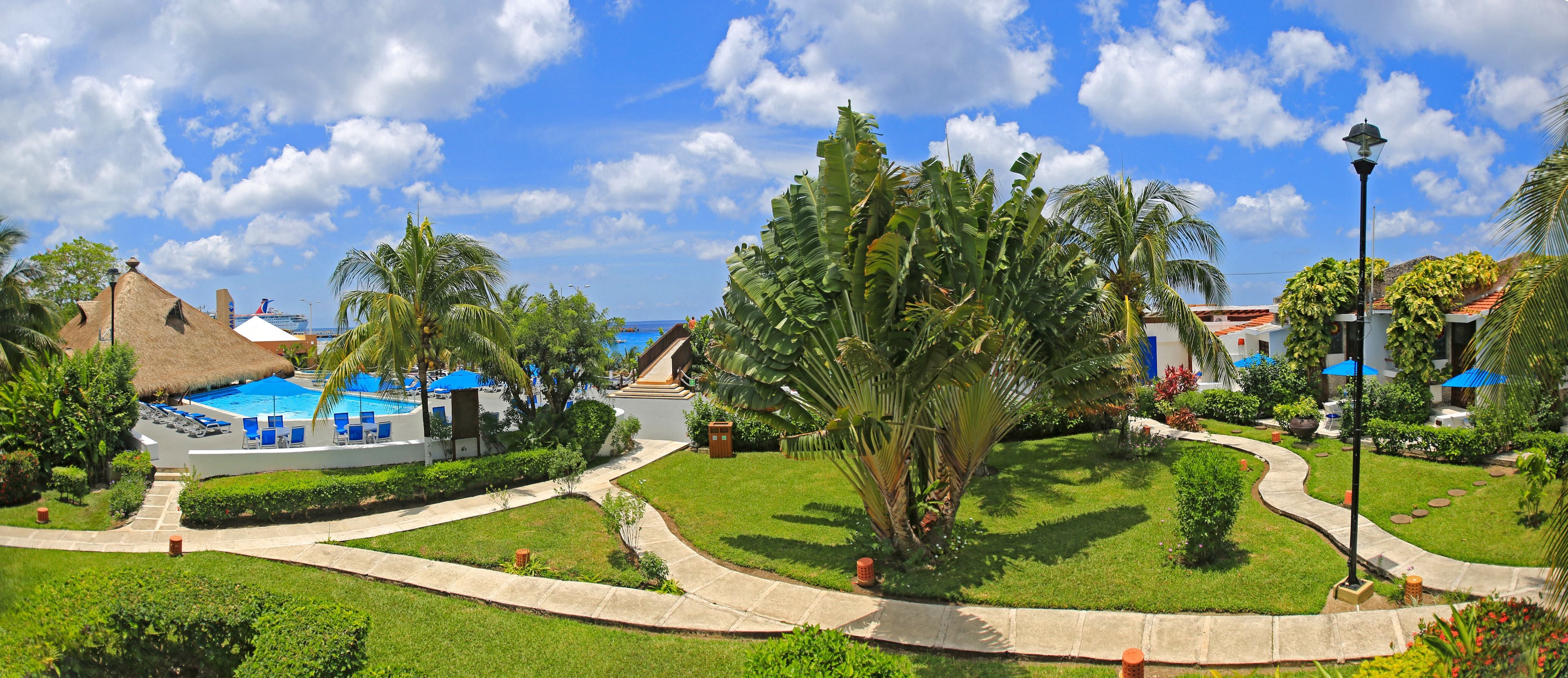 Ein Resort mit Schwimmbad, Palmen und einem gepflegten Garten.