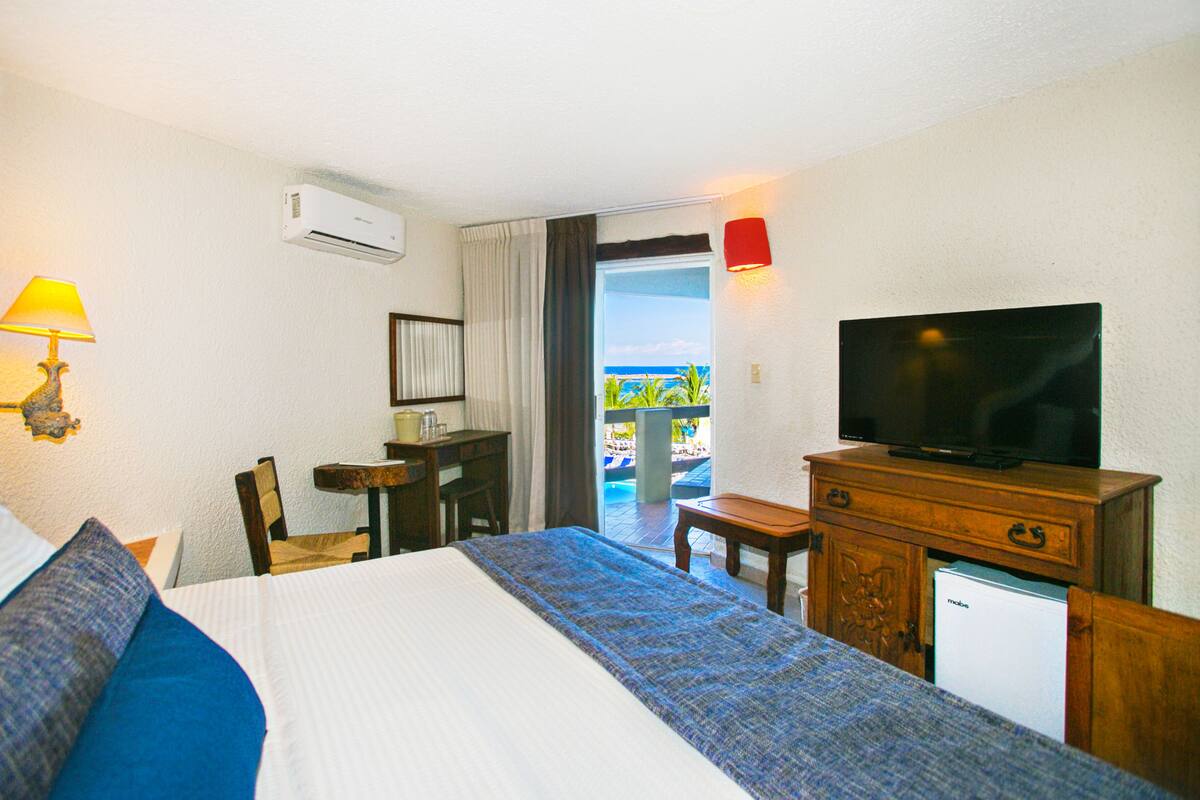 Une chambre d’hôtel équipée d’un lit, d’une télévision, d’un bureau et offrant une vue sur l’extérieur.