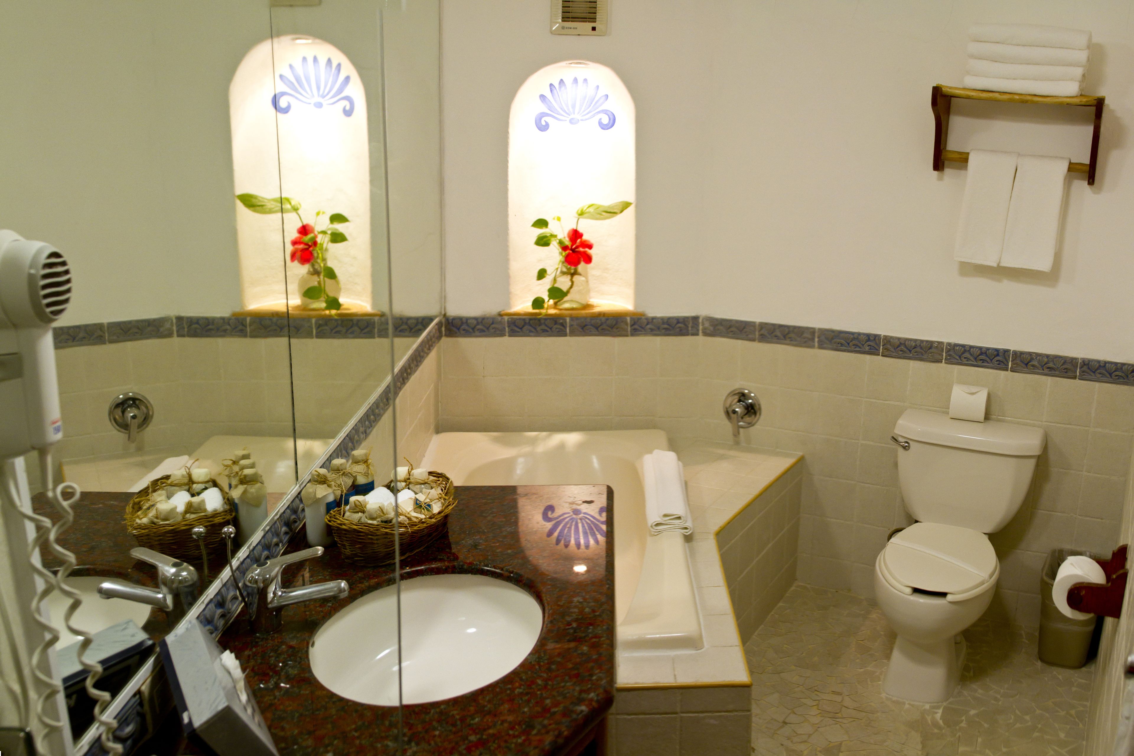 Ein Badezimmer mit Waschbecken, Spiegel, Waschtisch, Badewanne, Toilette und Handtuchhalter.