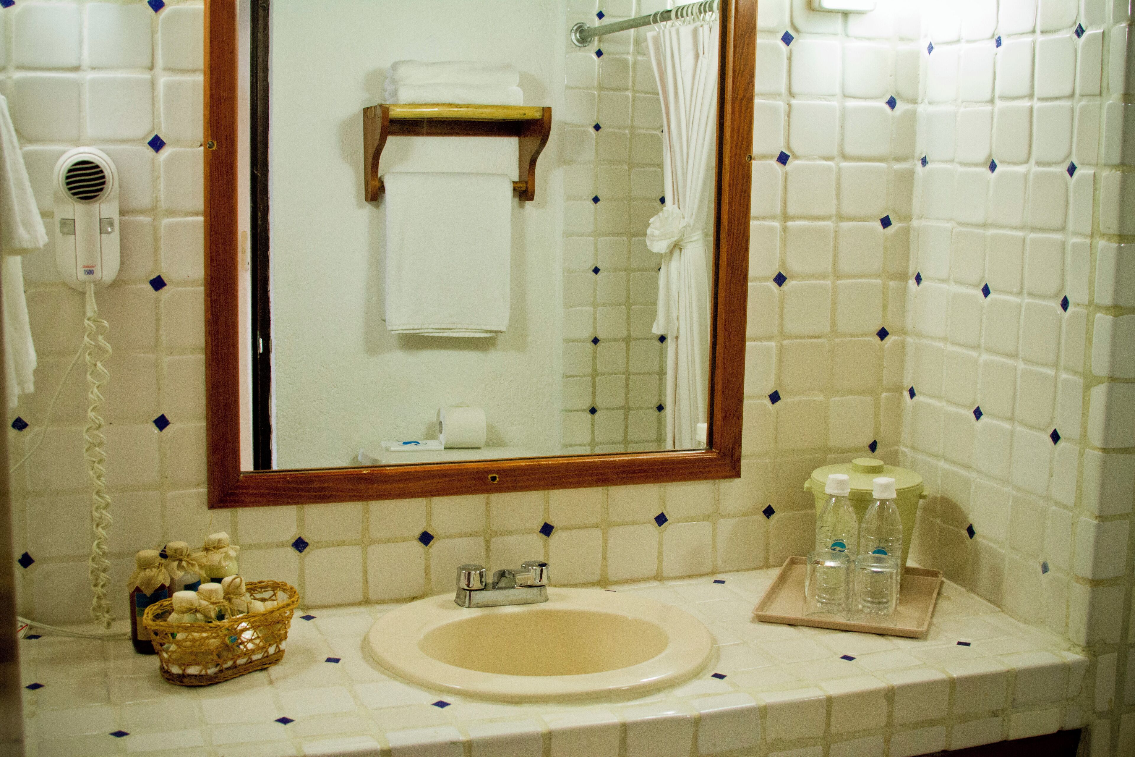 Un baño con lavamanos, espejo y perchero para toallas.