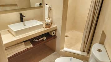 A bathroom with a white sink, a toilet, and a shower area.