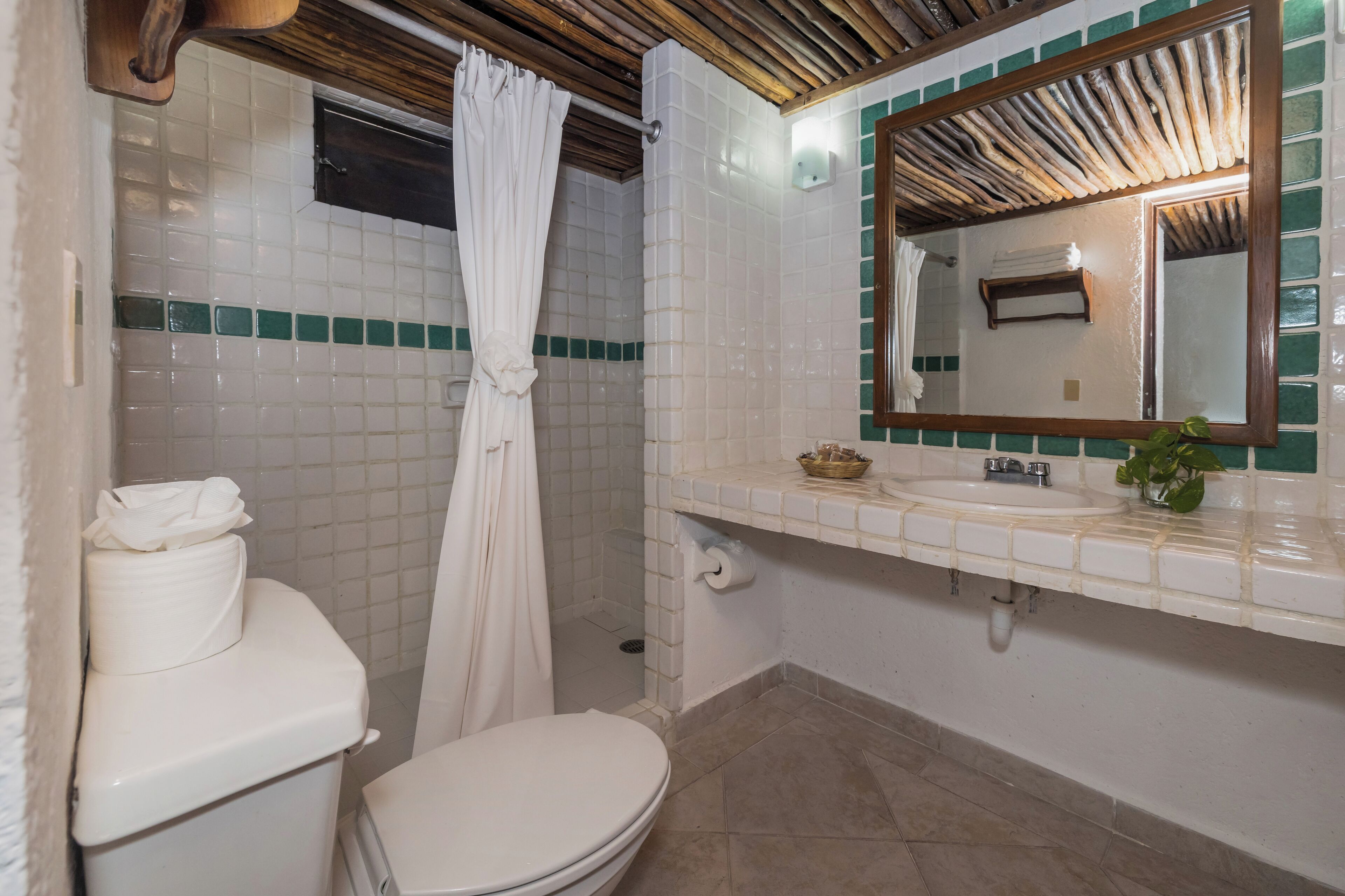 A bathroom with a toilet, shower, sink, and mirror.