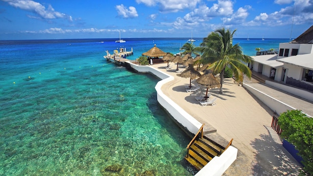 A beach resort with clear turquoise waters, a thatched-roof lounge area, and a white building with a balcony overlooking the sea. - Casa del Mar Cozumel Hotel & Dive Resort with Beach Club access included (Cozumel)