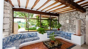A room with a stone wall, a wooden ceiling, a large window, and a blue patterned sofa. - Casa del Mar Cozumel Hotel & Dive Resort with Beach Club access included (Cozumel)