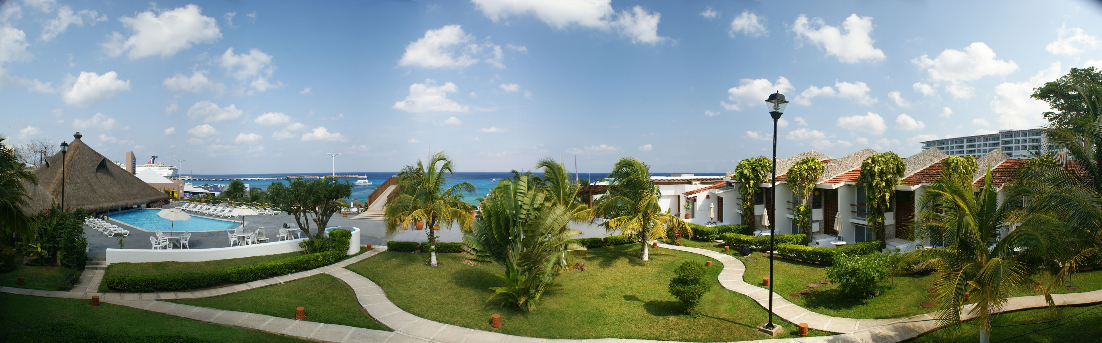 A resort with a swimming pool, palm trees, and a view of the ocean.