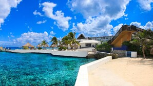 A resort with a clear blue ocean, a sandy beach, and a white building with a balcony overlooking the water. - Casa del Mar Cozumel Hotel & Dive Resort with Beach Club access included (Cozumel)