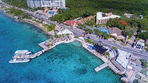 An aerial view of a coastal resort with a marina, clear turquoise waters, and a variety of buildings including hotels and resorts. - Casa del Mar Cozumel Hotel & Dive Resort with Beach Club access included (Cozumel)