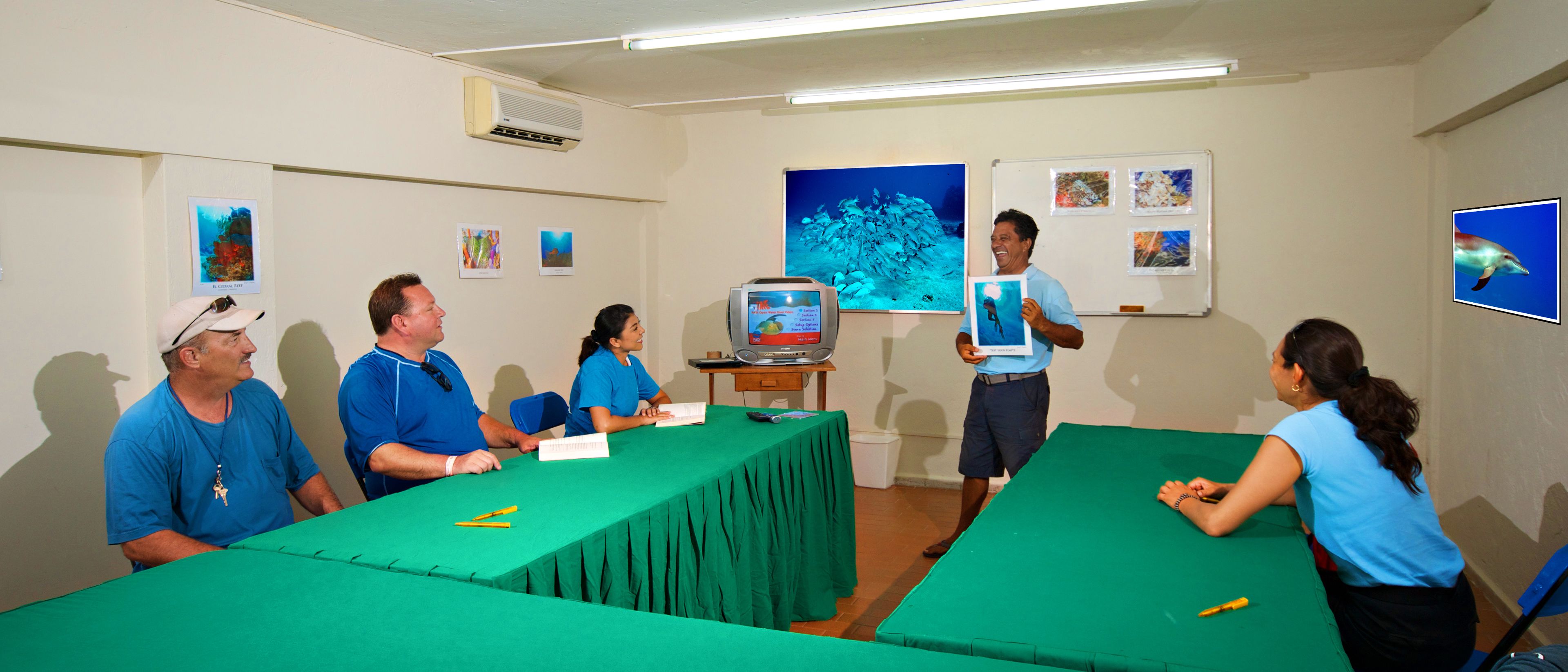 A conference room with a green table, a projector, and people seated.