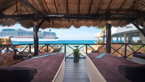 Una habitación junto a la playa con dos camas, vista al mar y un crucero en el fondo.