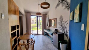 A room with a dining table, chairs, a blue cabinet, a hanging light fixture, and a view of a garden through a glass door. - Buena Vista Oceanfront & Hot Springs Resort (Buenavista)