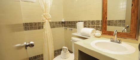 Un baño con inodoro, lavamanos y cortina de ducha.