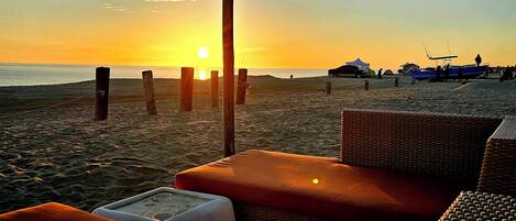 Un espace aménagé avec des sièges, situé au bord de la plage, d’où l’on peut admirer le coucher de soleil sur l’océan.