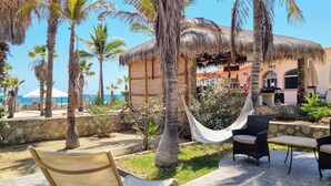 A beachside patio with a hammock, outdoor seating, and a thatched-roof structure. - Buena Vista Oceanfront & Hot Springs Resort (Buenavista)