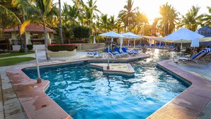 A swimming pool with lounge chairs and umbrellas, surrounded by palm trees and a building with a red-tiled roof. - Buena Vista Oceanfront & Hot Springs Resort (Buenavista)