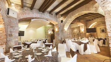 Un restaurante con paredes de ladrillo, vigas de madera y mesas dispuestas para comer.