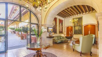 A lobby with a round table, sofas, and a chandelier.