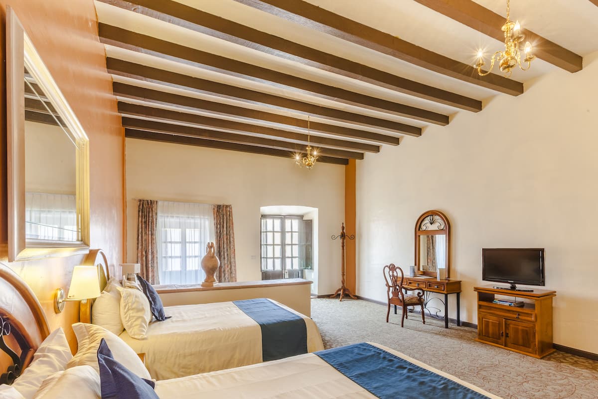Une chambre d’hôtel avec deux lits, une télévision, un bureau et un grand miroir.