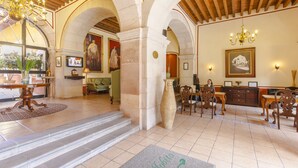 A spacious lobby with a high ceiling, arched columns, and a chandelier. There is a reception desk, seating area, and artwork on the walls. - Hotel Mesón de Jobito (Zacatecas)