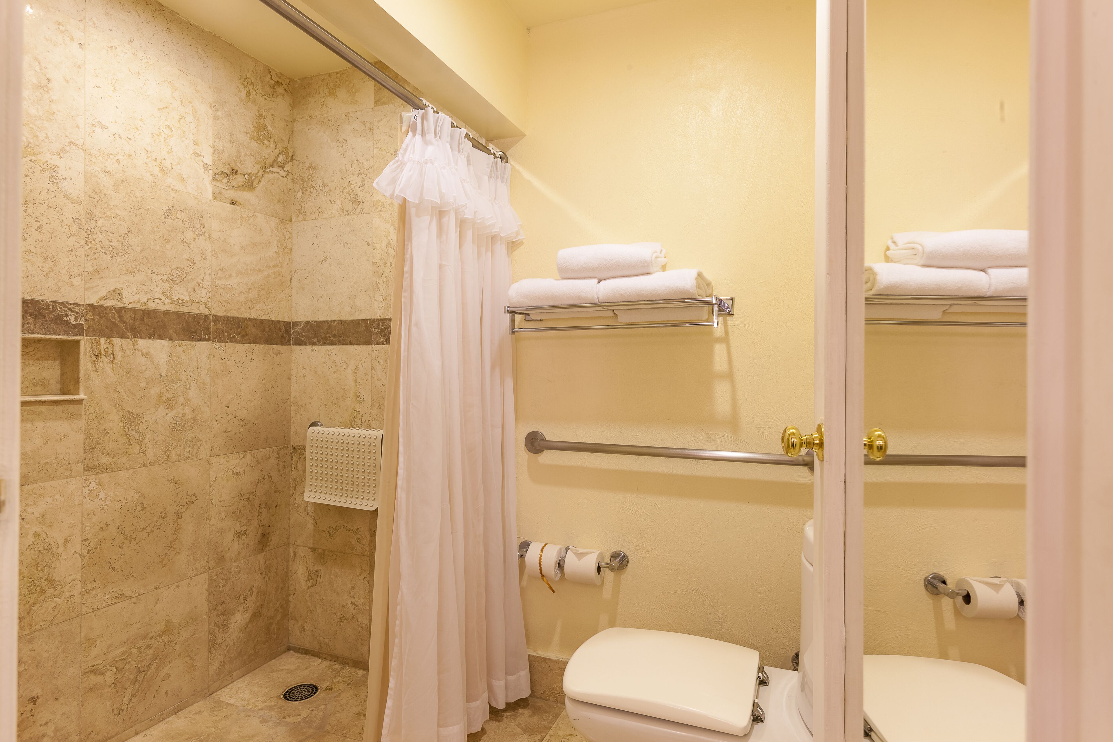 Un baño con ducha, inodoro y toallero.