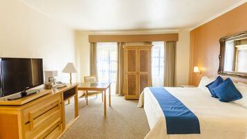 A hotel room with a bed, a TV, a desk, and a wardrobe.
