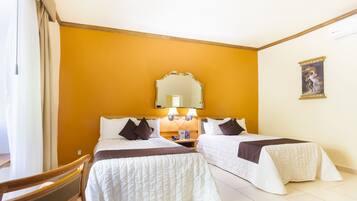A hotel room with two beds, a wooden headboard, a mirror, and a painting on the wall.