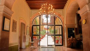 A grand entrance with a chandelier, arched doorways, and a staircase leading to a courtyard. - Hotel Mesón de Jobito (Zacatecas)