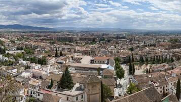 Vista panoràmica d'una ciutat amb arquitectura històrica, una església destacada i un paisatge de muntanyes al fons.