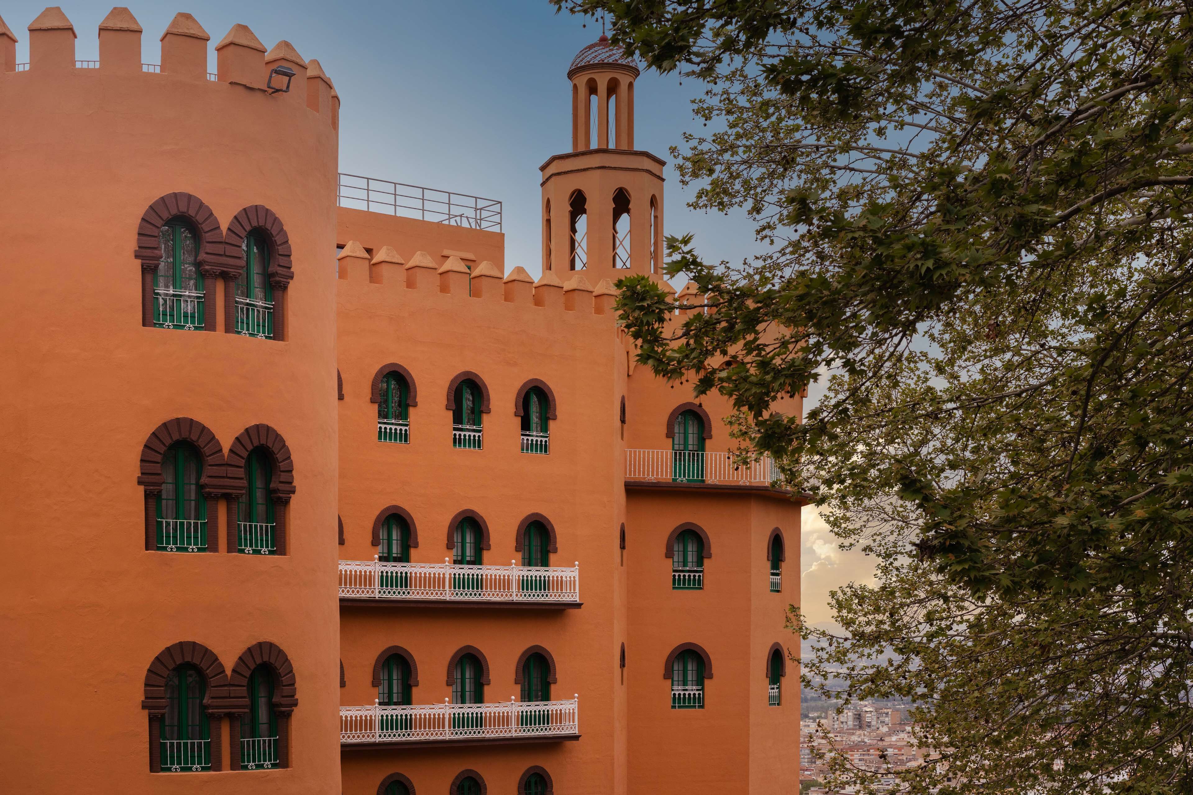 Un edificio de varios pisos con ventanas arqueadas y balcones, que presenta una torre con cúpula.
