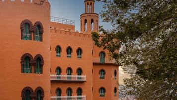 Un edificio de varios pisos con ventanas arqueadas y balcones, que presenta una torre con cúpula.