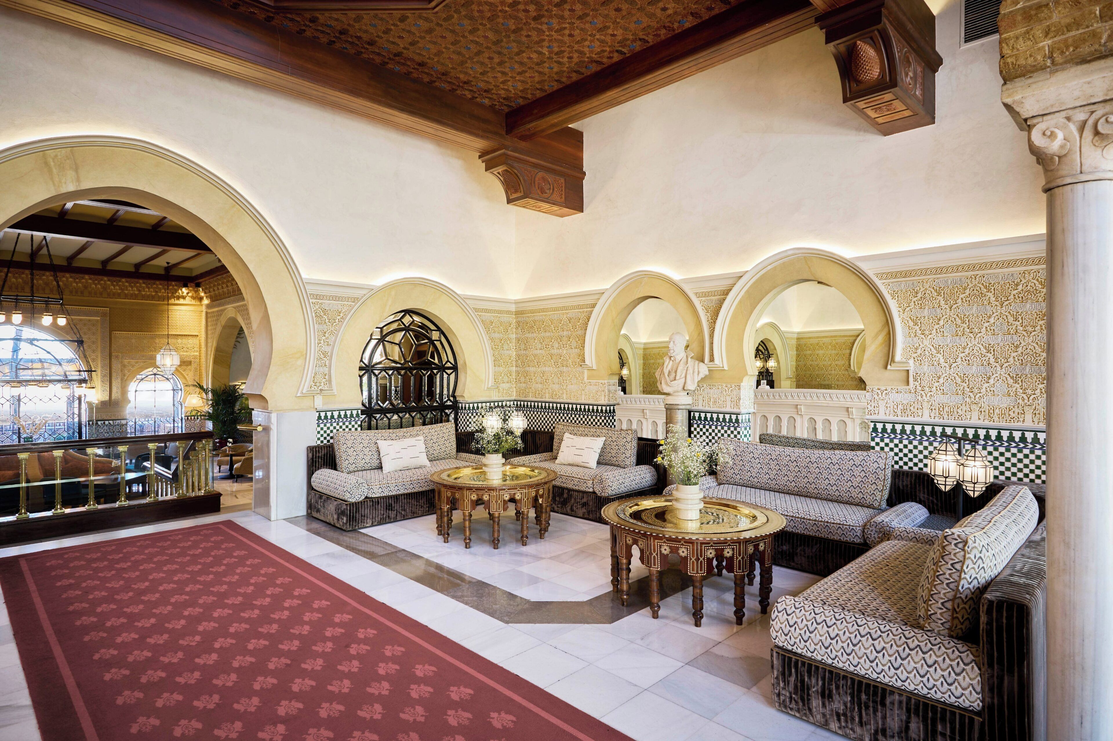 Eine Lobby mit rotem Teppich, Sofas und runden Tischen.