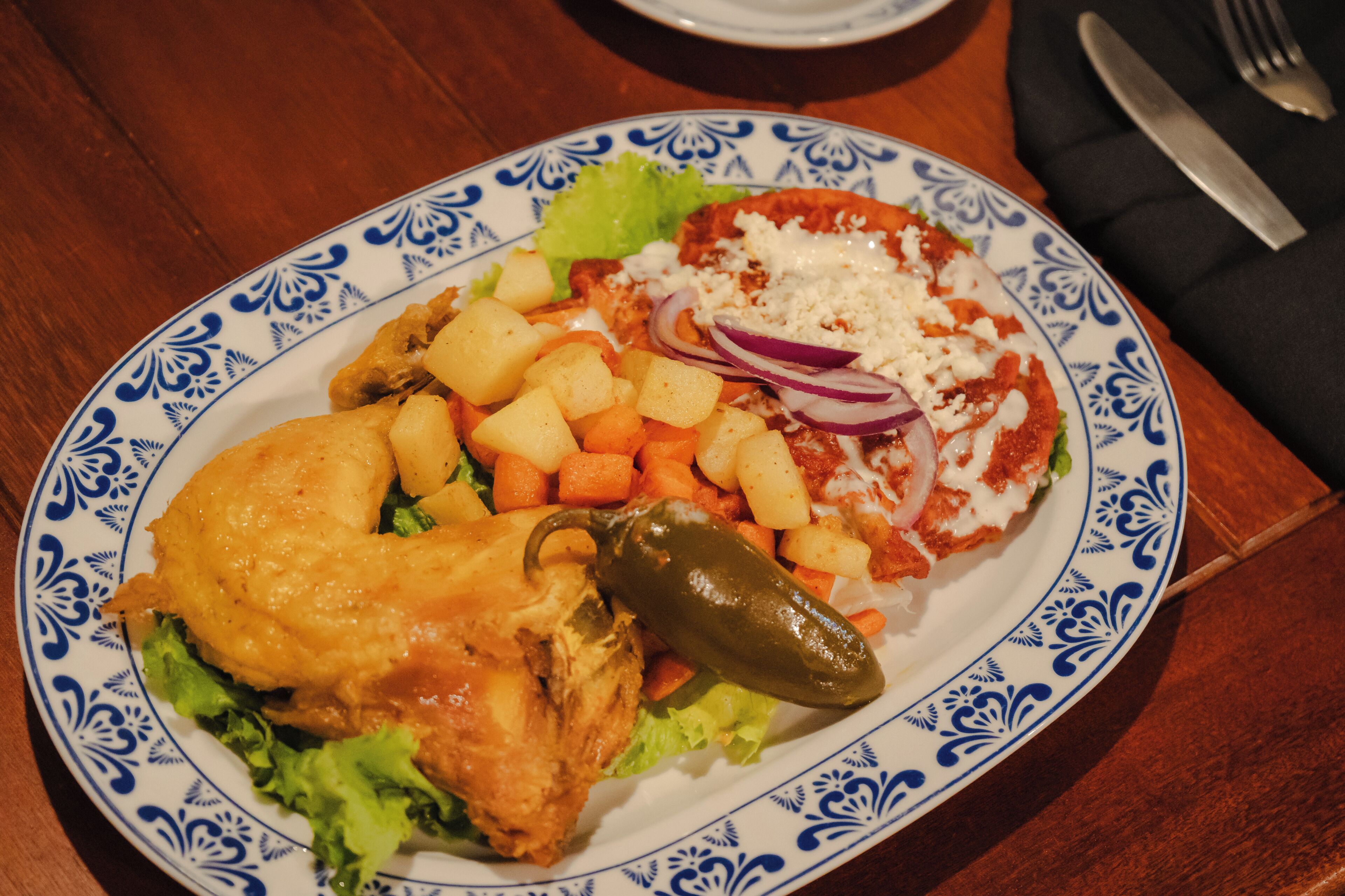 Un plato con pollo, verduras y salsa roja.