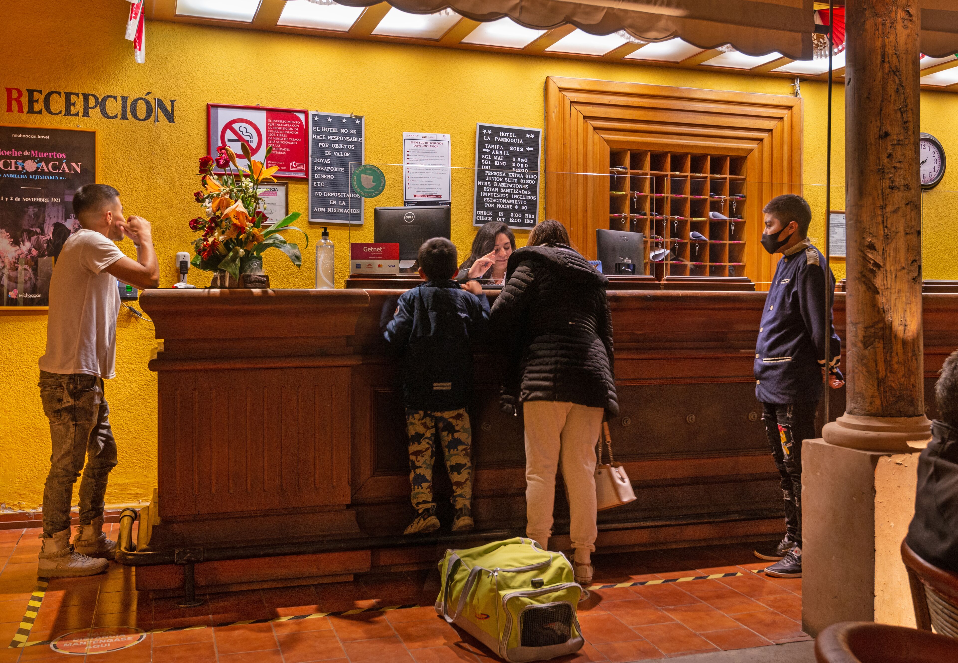 A reception area with a wooden counter, a clock, and various signs including a no smoking sign.