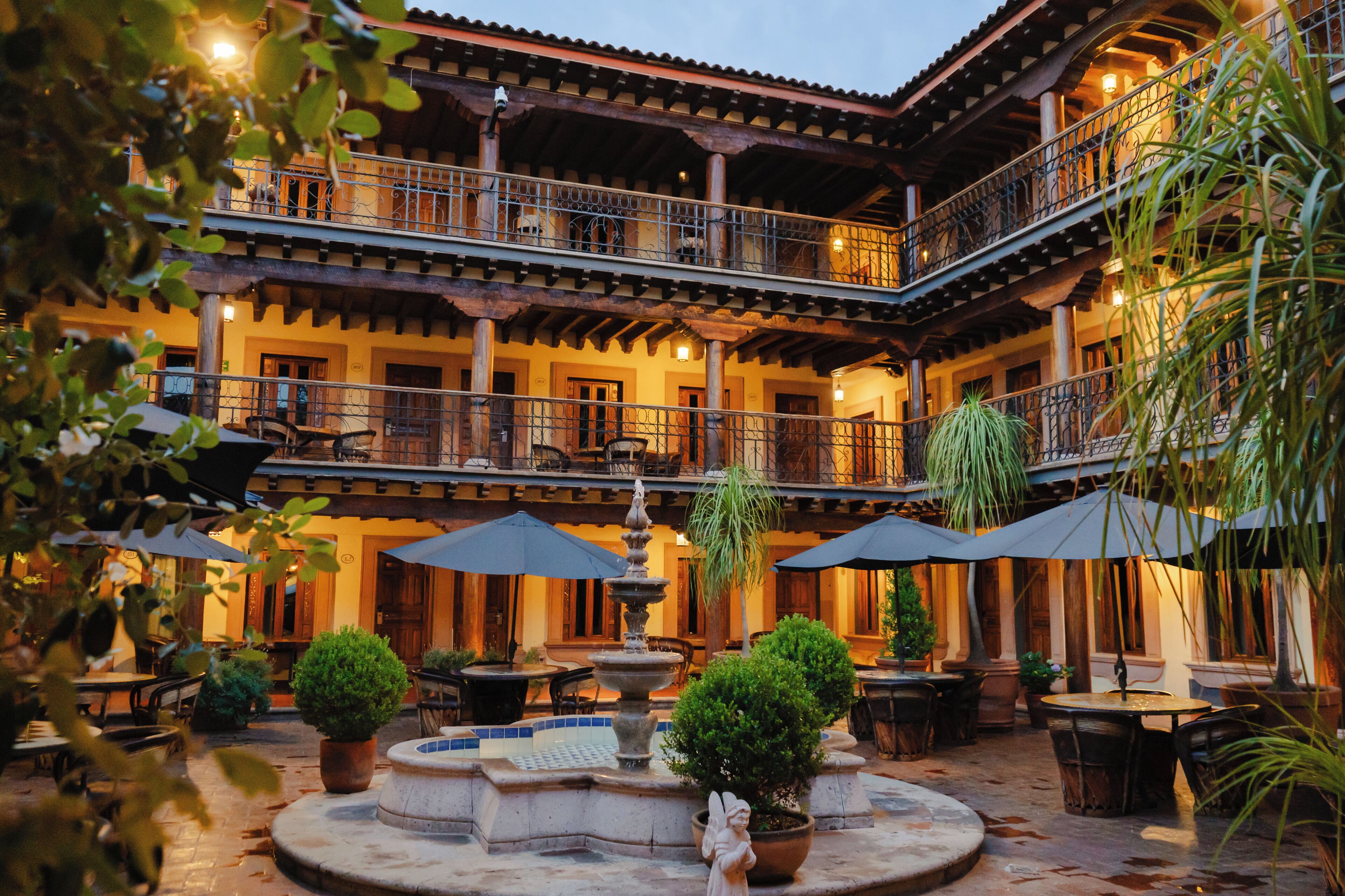 A courtyard with outdoor seating, a fountain, and potted plants.