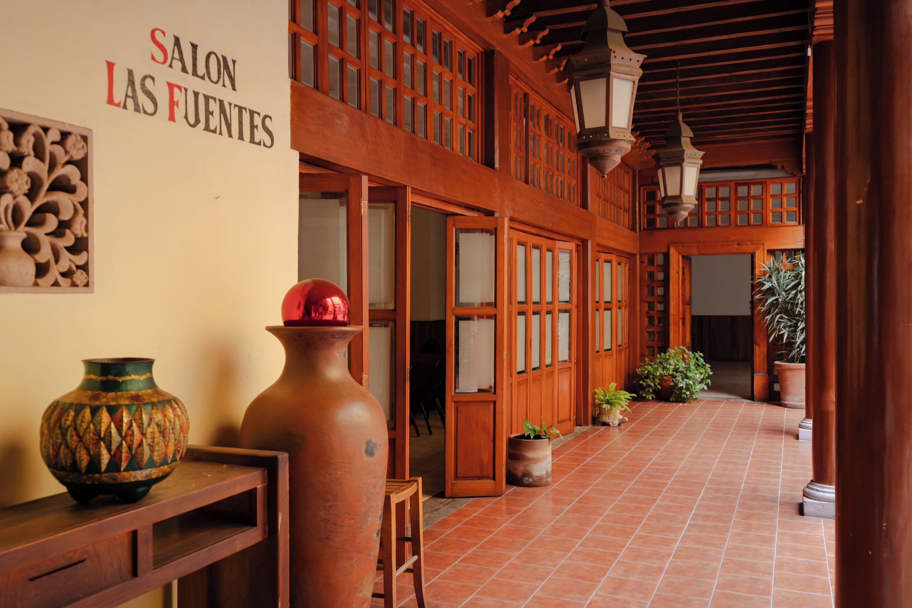 A traditional interior with wooden doors, a tiled floor, and a sign reading 'SALON LAS FUENTES'.