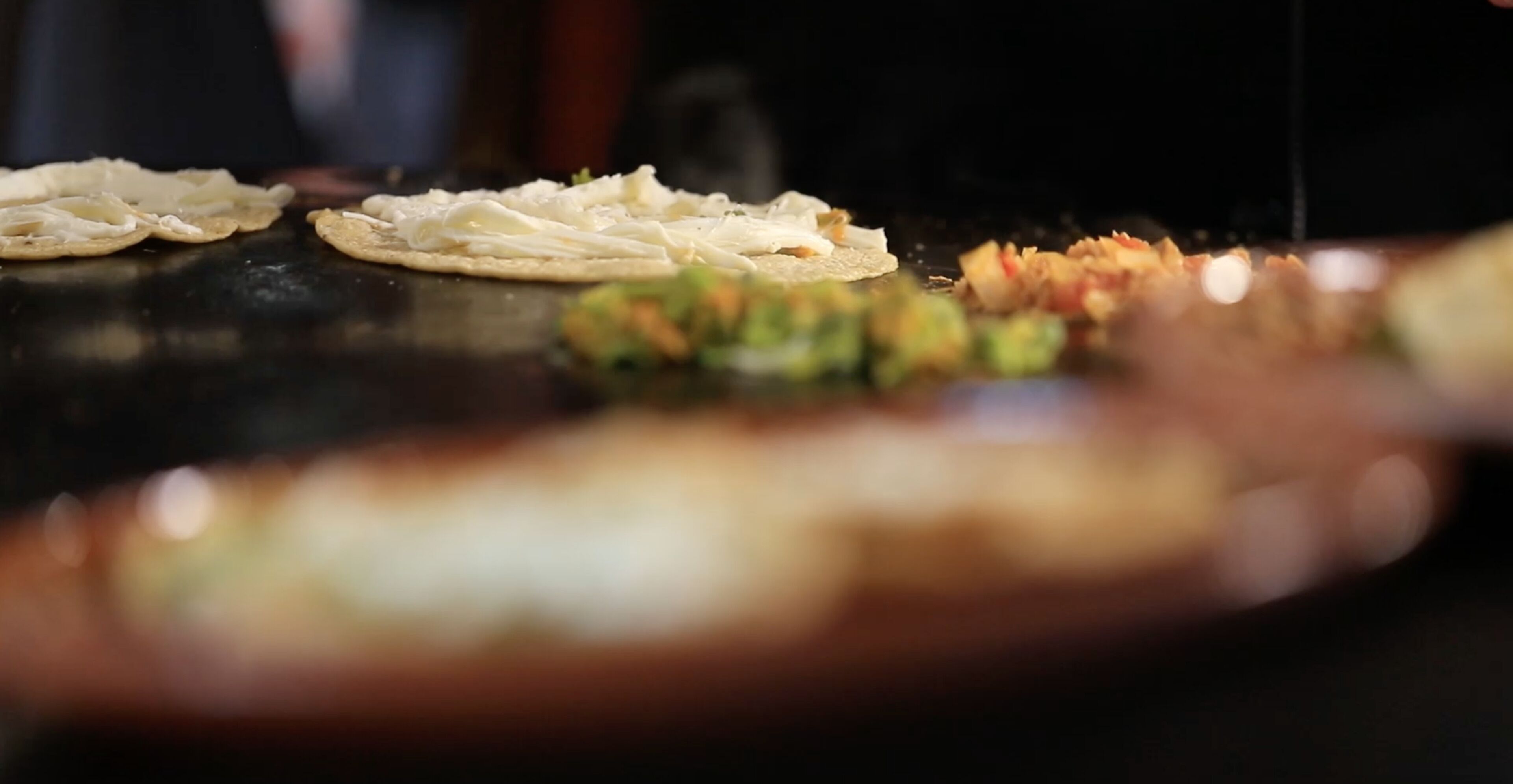 A blurred view of a dining table with food items, possibly a meal being prepared or served.