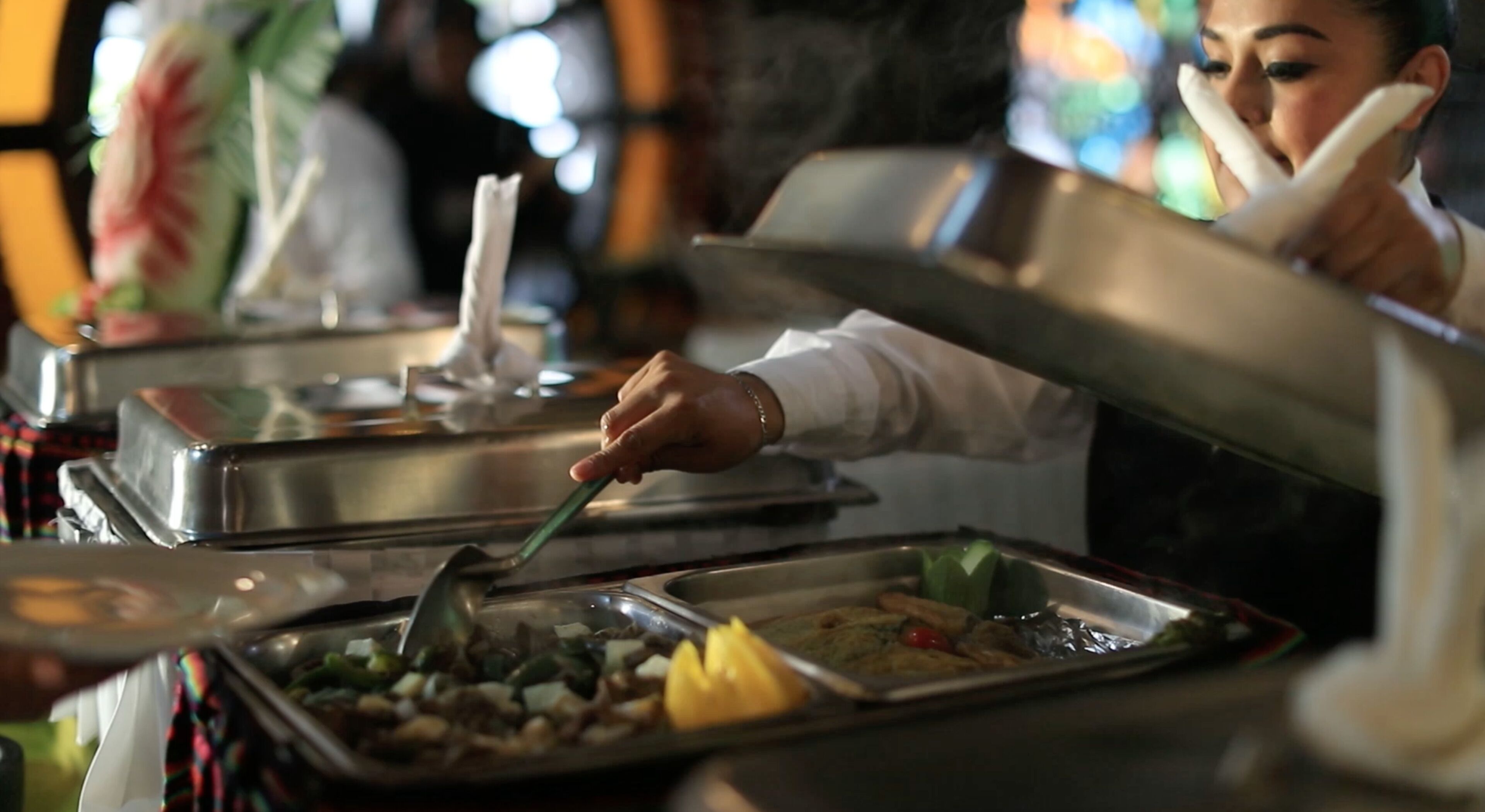 A buffet setup with various food items and a person serving.