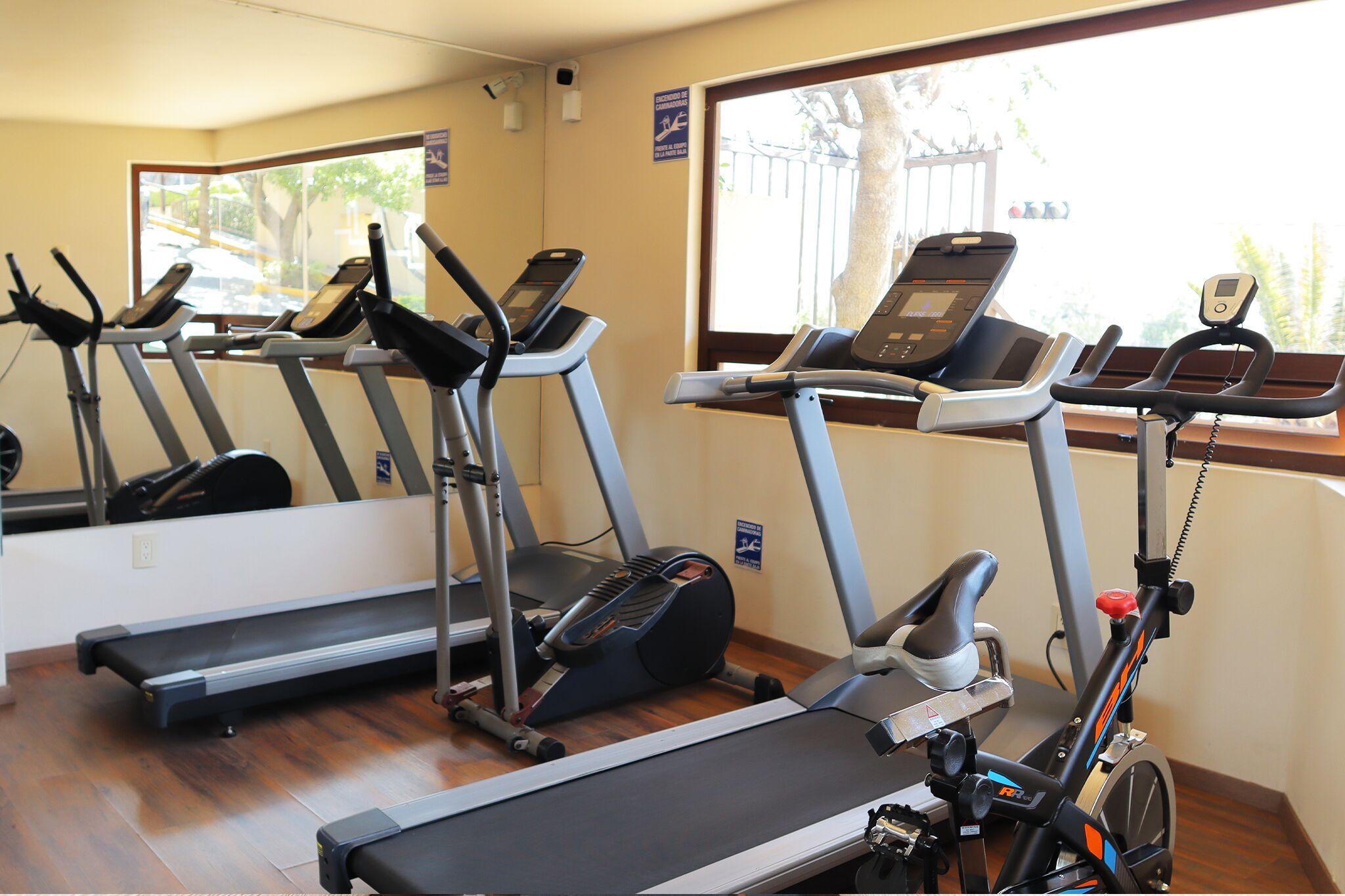 Ein Fitnessraum mit Laufbändern, einem Ergometer und einem Spiegel.