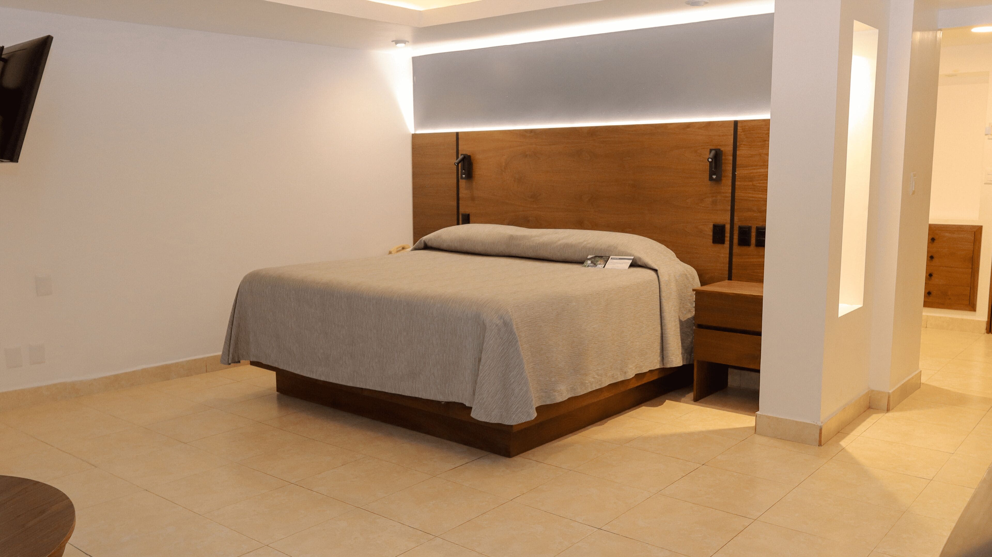 A modern bedroom with a bed, bedside tables, and a wooden headboard.