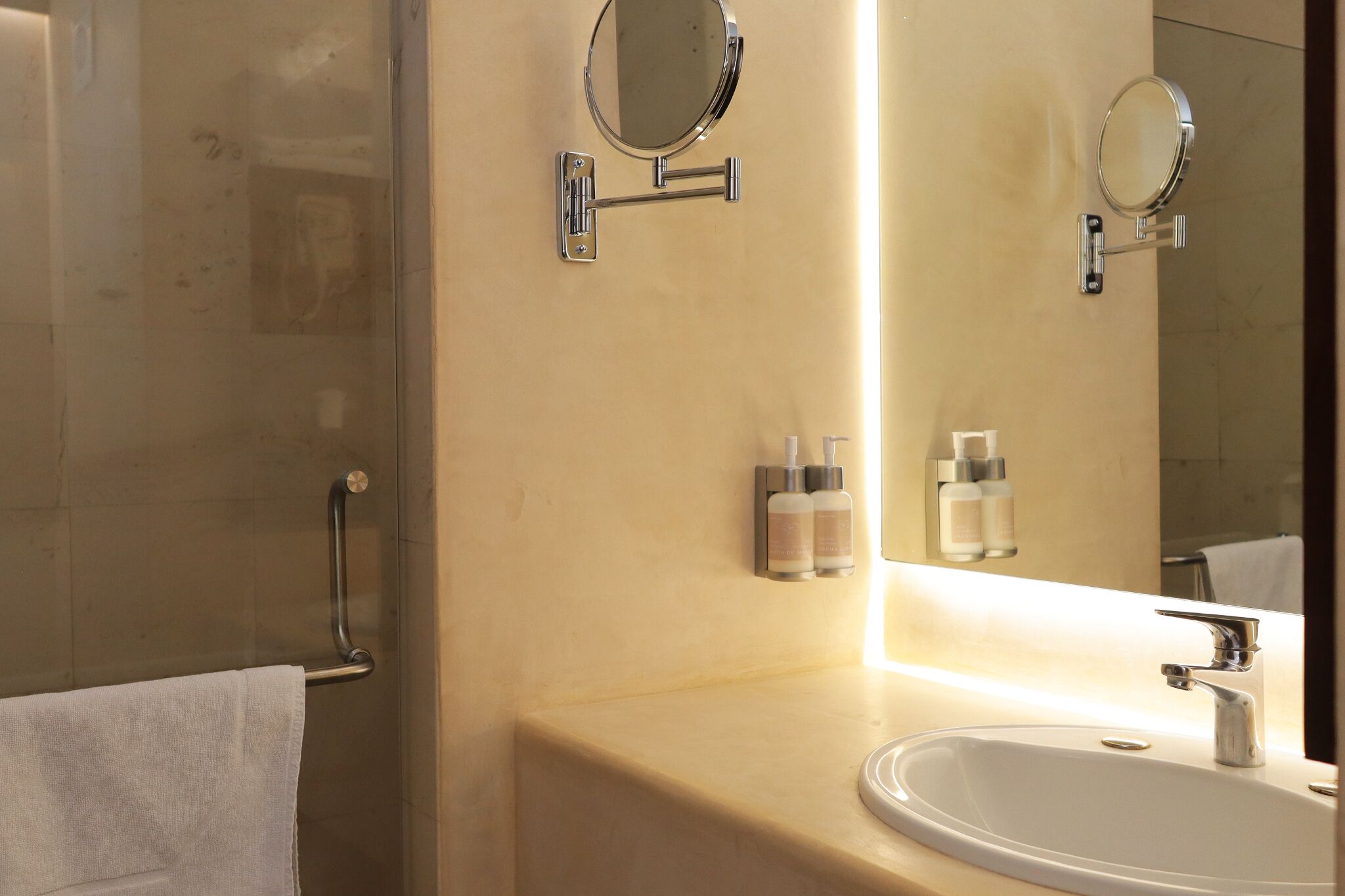 A bathroom with a sink, mirror, towel rack, and two bottles of toiletries.