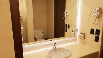 Ein Badezimmer mit Waschbecken, Spiegel, Fön und Toilettenartikeln.
