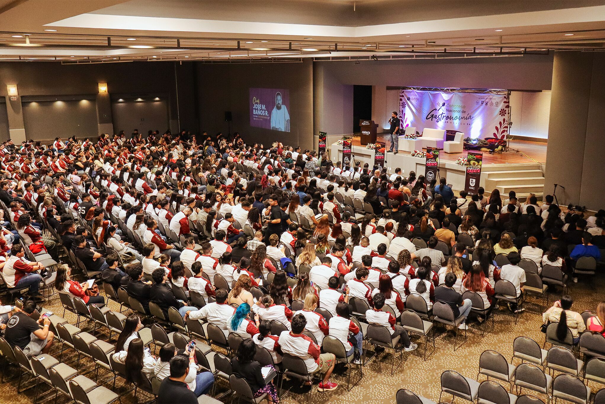 A large indoor auditorium with rows of chairs facing a stage.