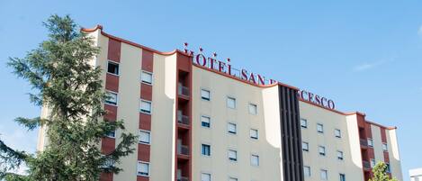 Un hotel de varios pisos con un letrero llamativo que dice "HOTEL SAN CESCO".