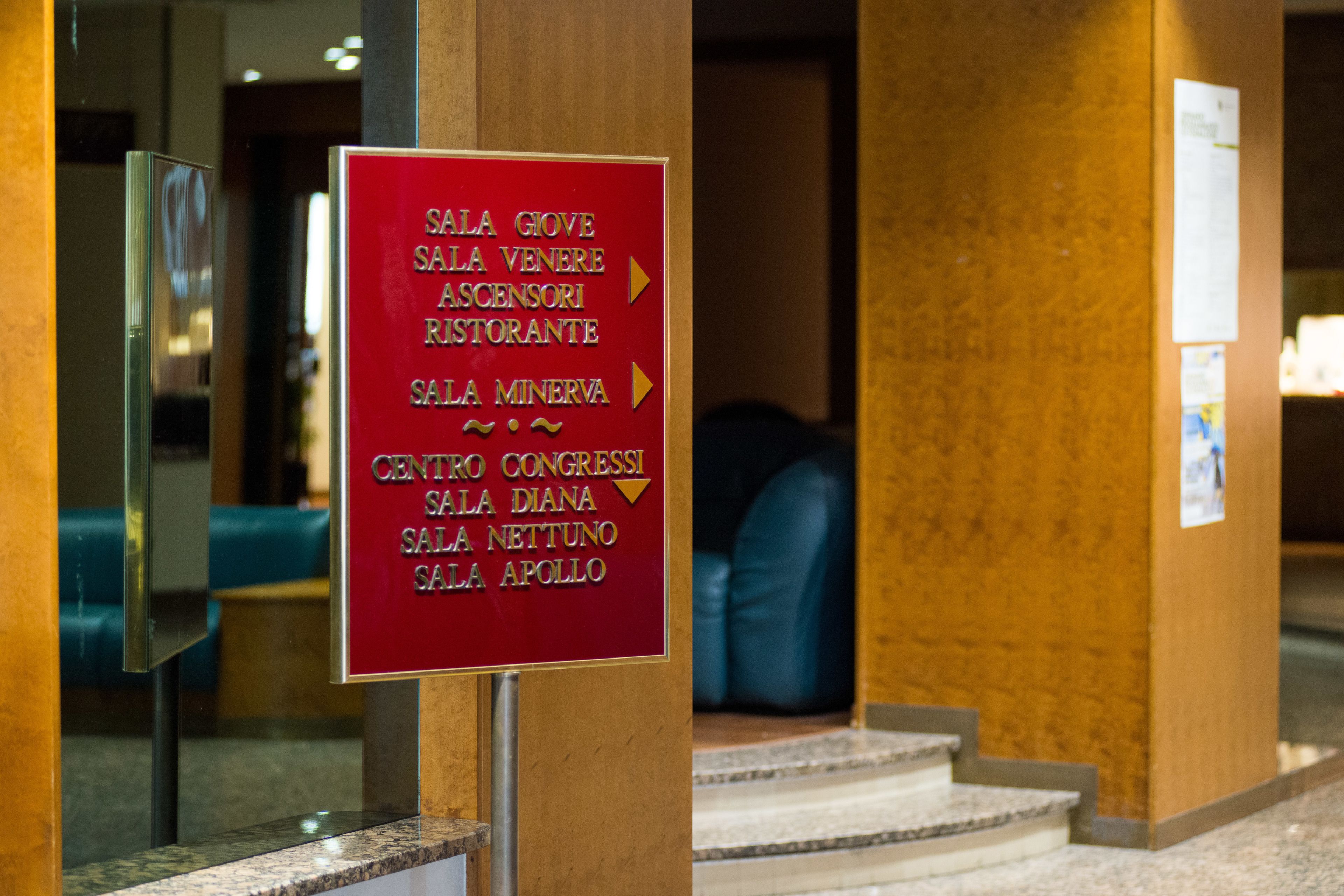 Un letrero con nombres de habitaciones e indicaciones en el vestíbulo de un hotel.